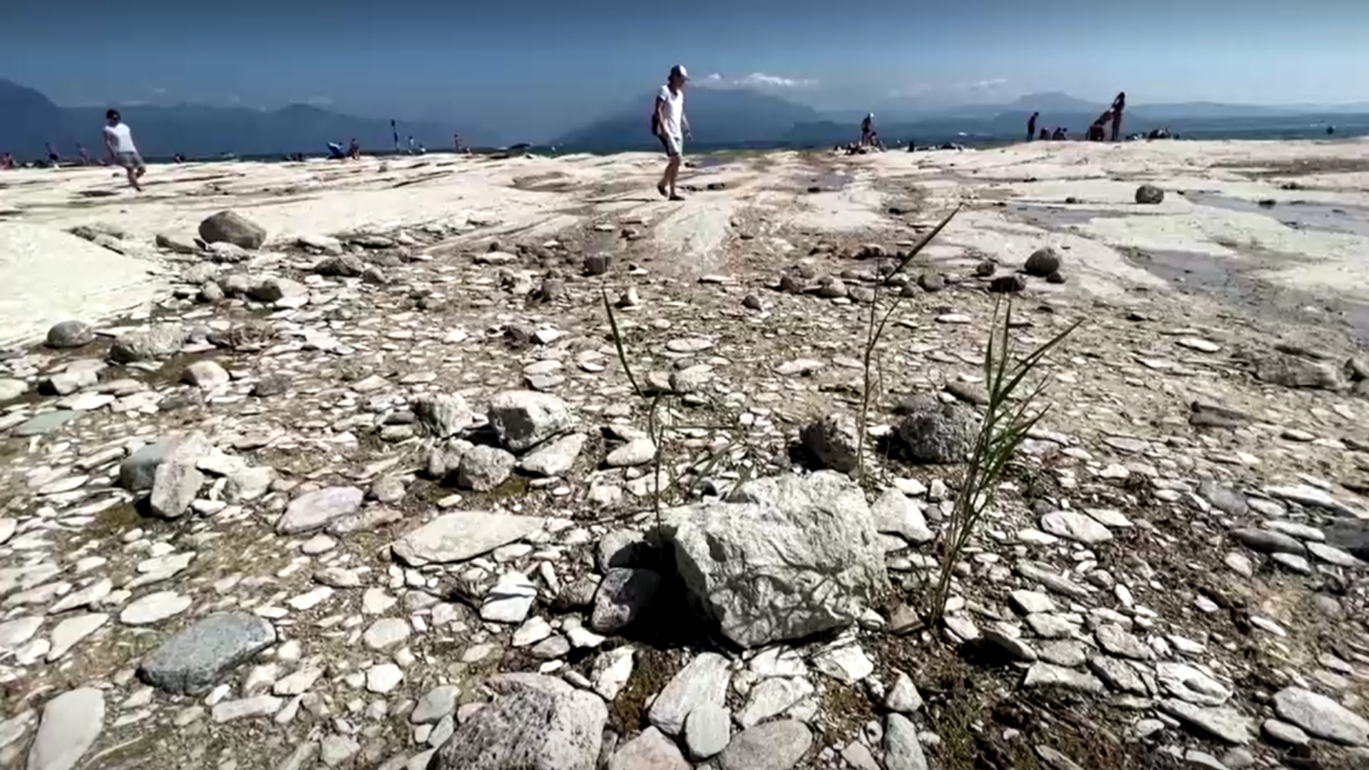Turista caminha no leito do Lago Garda, na Itália em meio a seca / Reprodução / Reuters