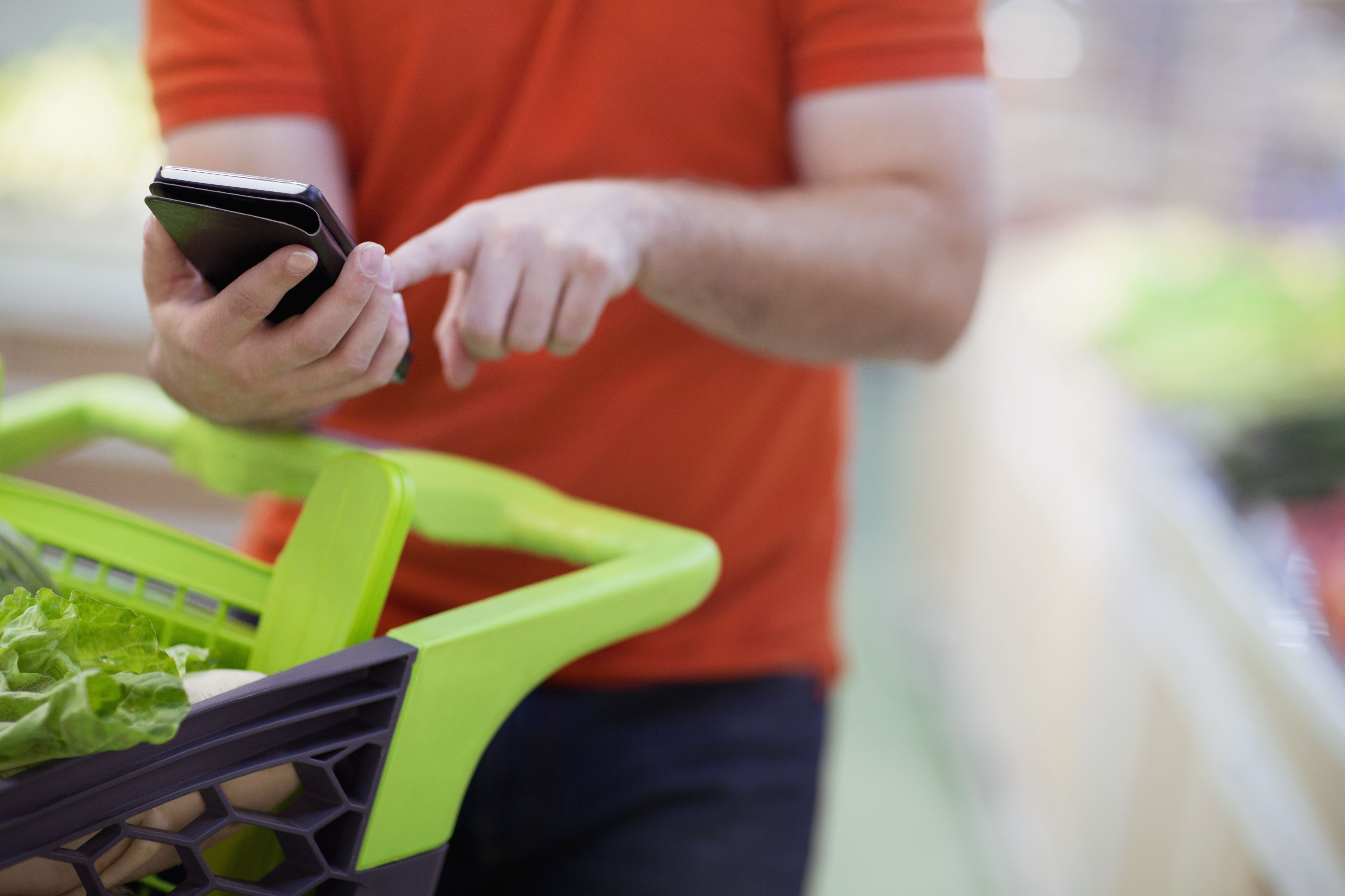 Man texting on smart phone while shopping for groceries