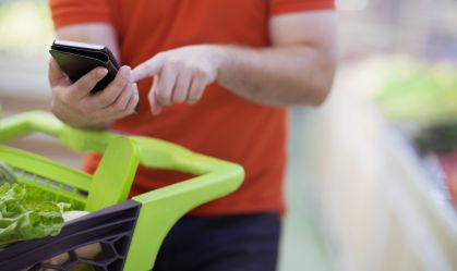 Man texting on smart phone while shopping for groceries