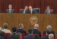Sentados lado a lado, Bolsonaro e Moraes cochicham e riem em posse