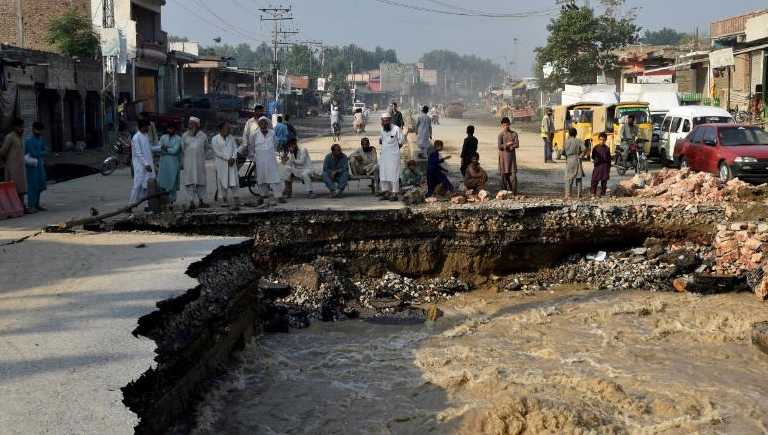 Moradores se reúnem ao lado de uma estrada danificada pelas águas das enchentes após fortes chuvas de monção no distrito de Charsadda, em Khyber Pakhtunkhwa, em 29 de agosto de 2022. Reprodução/Aboul Majeed/AFP/Getty Images