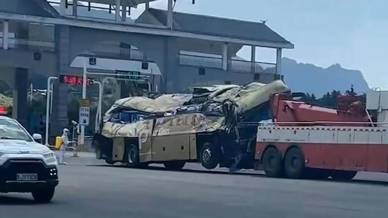 Homem com roupas de proteção contra a Covid-19 pulveriza ônibus destruído com desinfetante na China