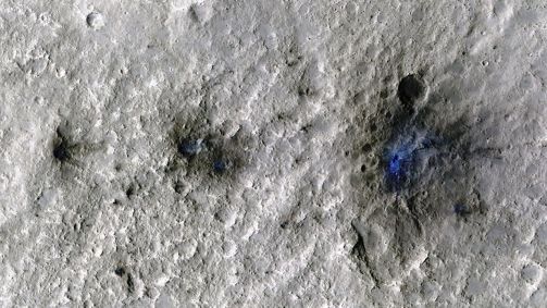 Impacto de meteoroide formou essas crateras em Marte em setembro de 2021. Esta imagem, tirada pela Mars Reconnaissance Orbiter, realça a poeira e o solo deslocados em azul para tornar os detalhes mais visíveis