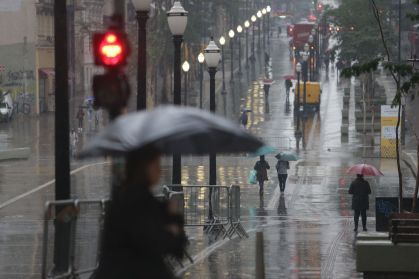 Pedestres se protegem do frio e da chuva no centro da cidade de São Paulo nesta segunda-feira (26)