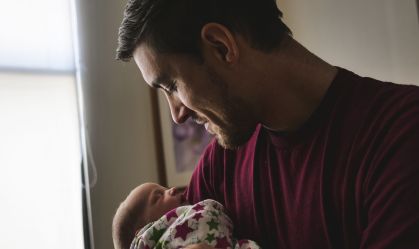 Father looking at newborn son sleeping at hospital