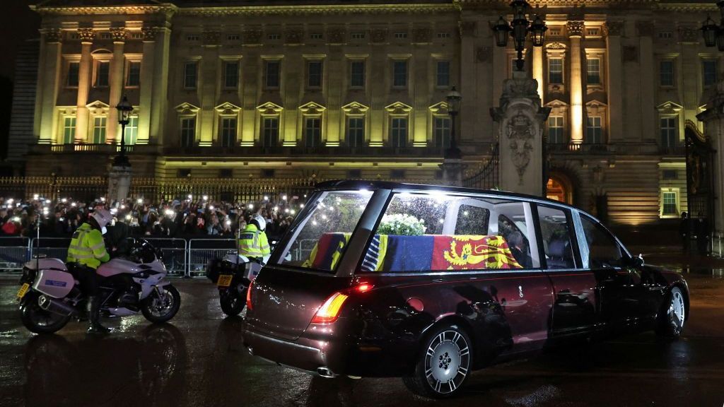 Carro funerário carregando o caixão coberto de bandeira da rainha Elizabeth II entra no portão central do Palácio de Buckingham