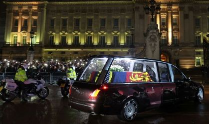 Carro funerário carregando o caixão coberto de bandeira da rainha Elizabeth II entra no portão central do Palácio de Buckingham