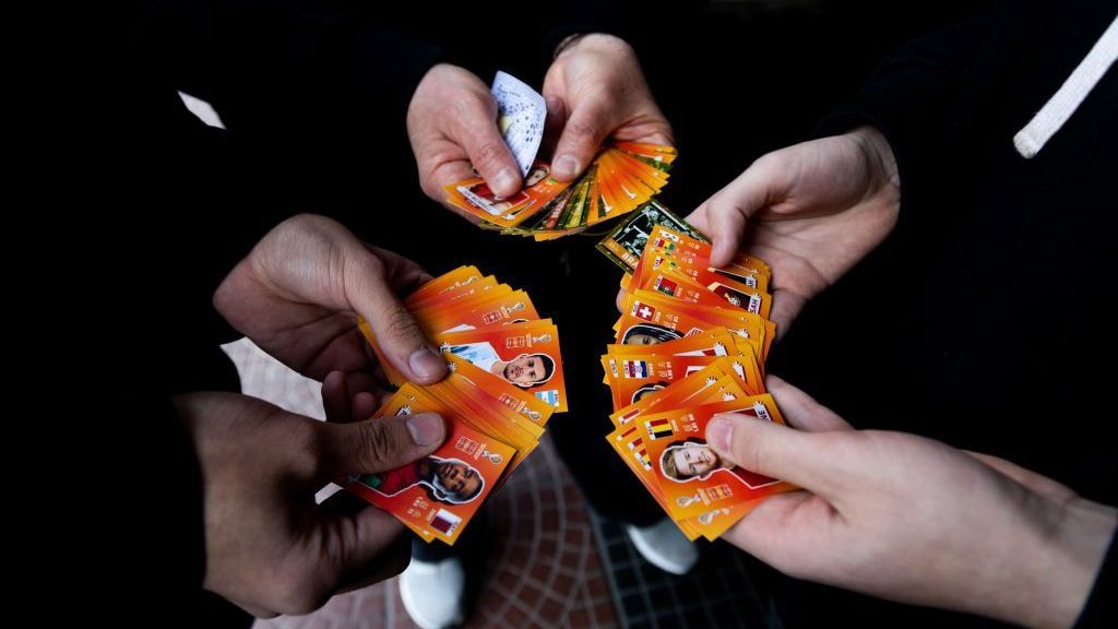Pessoas trocam figurinhas enquanto esperam na fila para comprar novos cromos em um quiosque que acaba de receber estoque em 21 de setembro de 2022, em Buenos Aires, Argentina