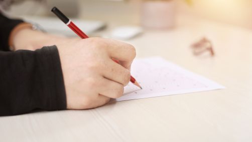 Pessoa escrevendo em um pedaço de papel com lápis