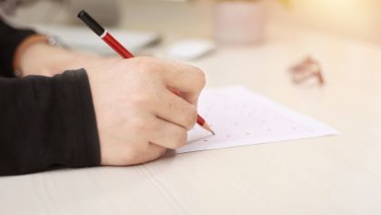 Pessoa escrevendo em um pedaço de papel com lápis