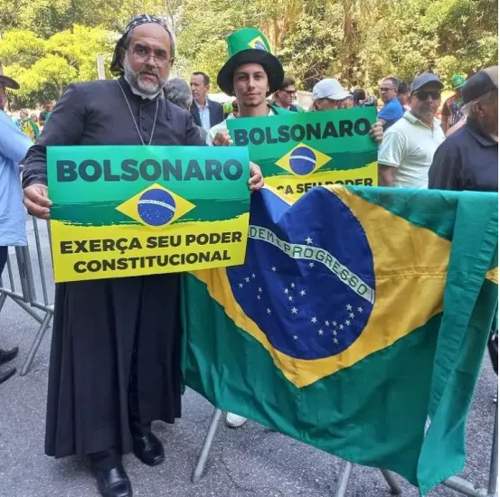 | Padre Kelmon ergue cartaz com mensagem criminosa durante manifestação bolsonaristas de 1º de maio de 2022 em São Paulo. Fonte: Instagram do Padre Kelmon / Projeto Comprova