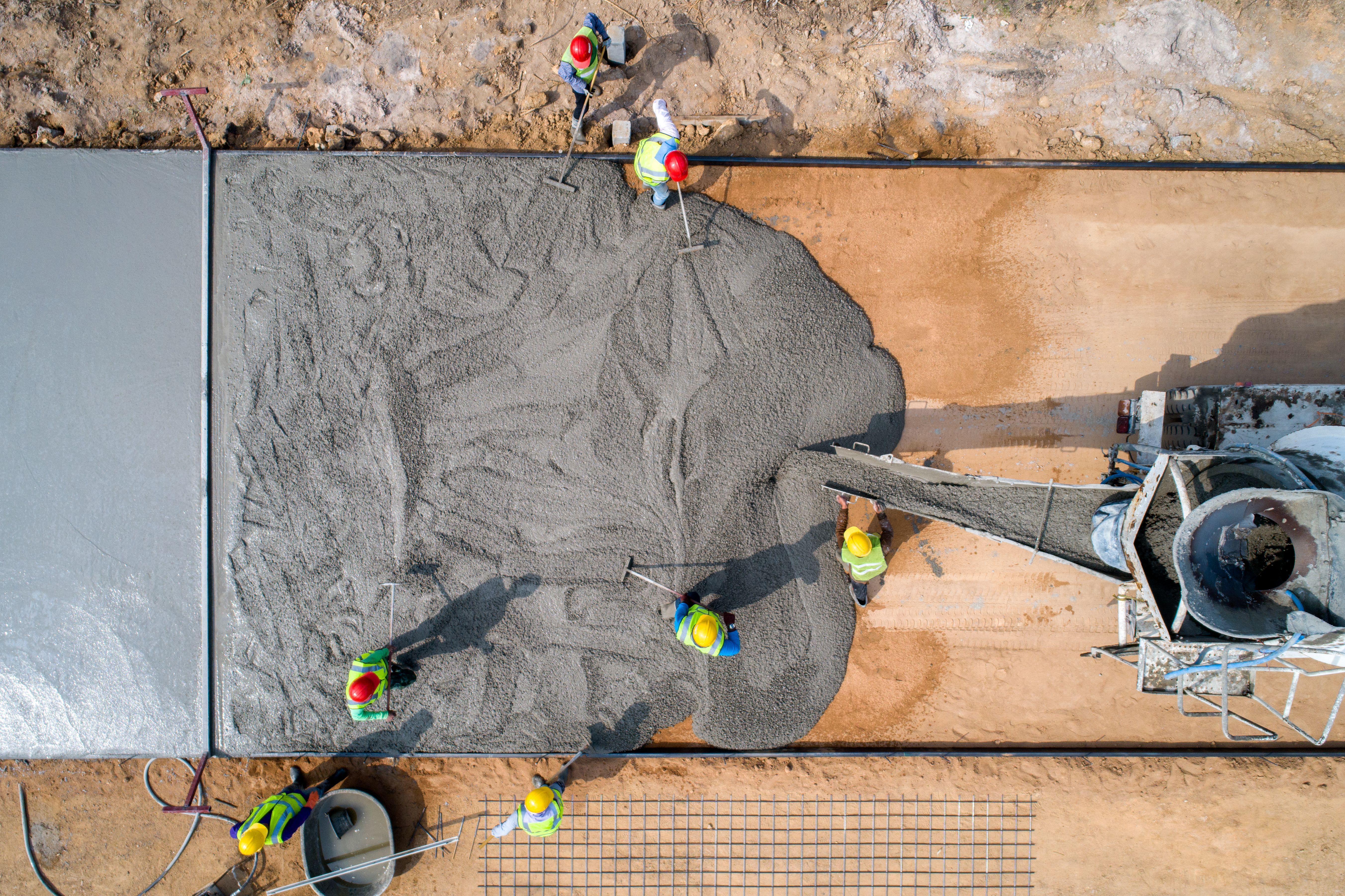 A construction worker pouring a wet concret at road construction site