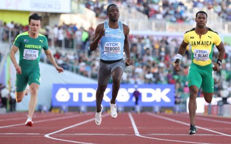 Jake Doran, do Time Austrália, Letsile Tebogo, da Equipe Botsuana, e Yohan Blake, da Equipe Jamaica, competem nas eliminatórias dos 100 metros masculinos no primeiro dia do Campeonato Mundial de Atletismo Oregon22