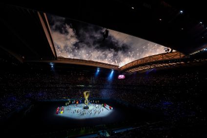 Visão geral da cerimônia de abertura da Copa do Mundo do Catar, com dançarinos em campo ao redor do logo do Mundial.
