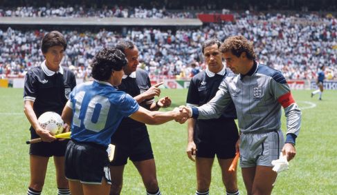 Diego Maradona (esq.) aperta a mão de Peter Shilton (dir.) sob os olhares do árbitro Ali Ben Nasser (centro) antes da partida entre Argentina e Inglaterra pelas quartas de final da Copa do Mundo de 1986, no México