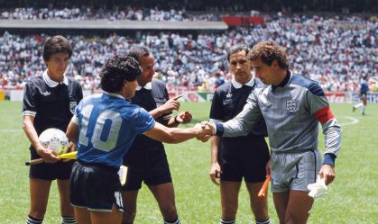 Diego Maradona (esq.) aperta a mão de Peter Shilton (dir.) sob os olhares do árbitro Ali Ben Nasser (centro) antes da partida entre Argentina e Inglaterra pelas quartas de final da Copa do Mundo de 1986, no México
