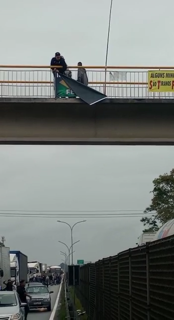 Torcedores do Corinthians retiram faixas que pediam intervenção militar após desmontar bloqueio de apoiadores do presidente Jair Bolsonaro, na rodovia Presidente Dutra. / Reprodução