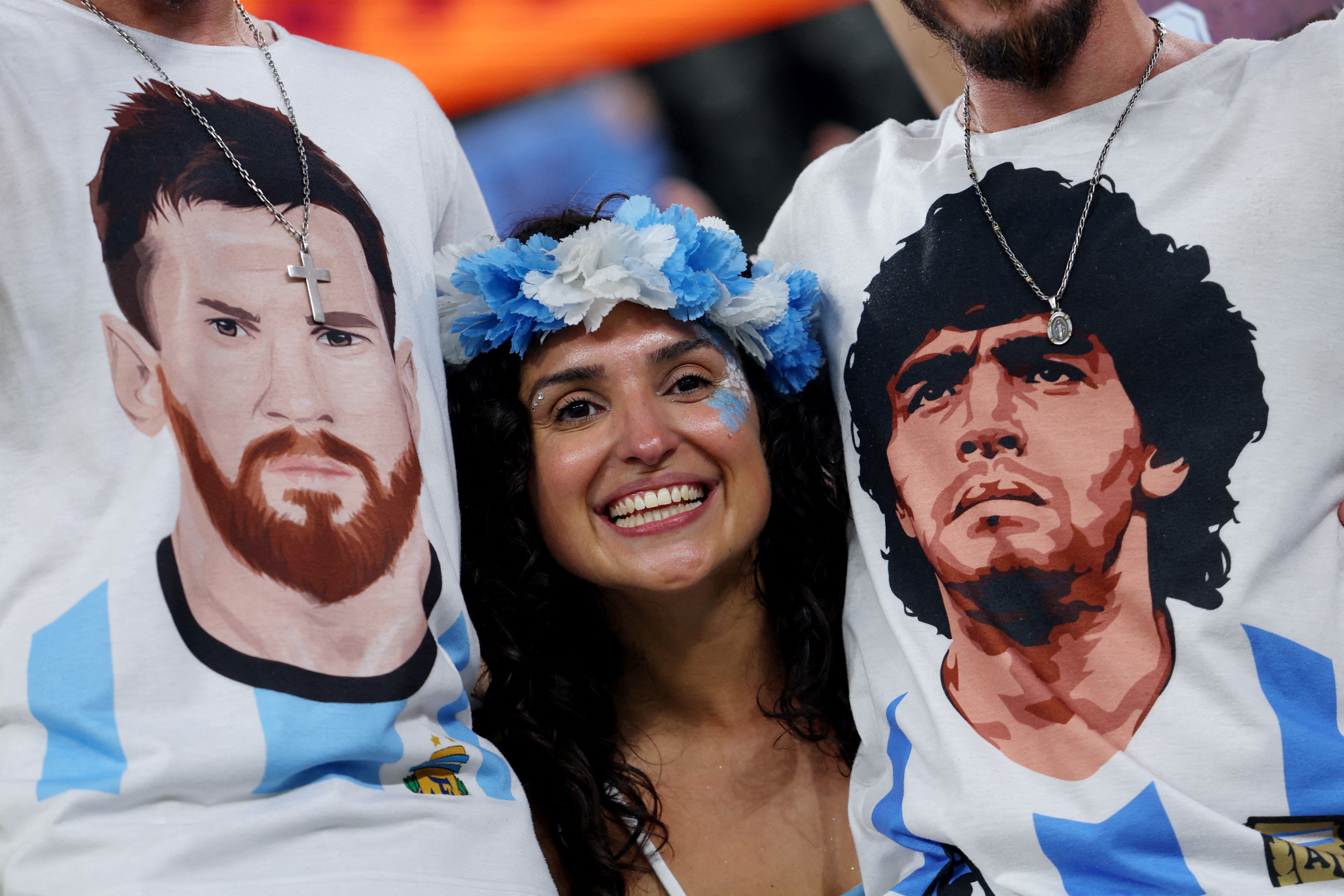 Torcedora da Argentina junto a torcedores com camisas com as imagens de Lionel Messi e Diego Maradona antes de partida contra a Polônia na Copa do Mundo do Catar