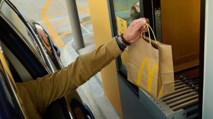 Um cliente pega um pedido do McDonald's em uma esteira.