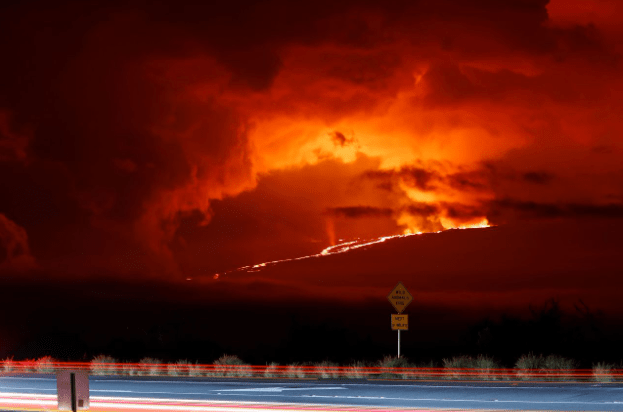 Nesta foto de longa exposição, os carros dirigem pela Saddle Road em 28 de novembro, enquanto o Mauna Loa entra em erupção à distância. Marco Garcia/AP