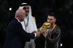 Ao lado de Gianni Infantino, presidente da Fifa, e do Emir do Qatar, Lionel Messi beija a taça da Copa do Mundo 2022; craque vestiu traje real com fios de ouro