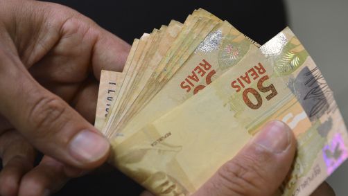 Pessoa segurando notas de 50 reais