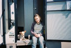 Bella Ramsey com um cachorro em trailer no set da série The Last of Us