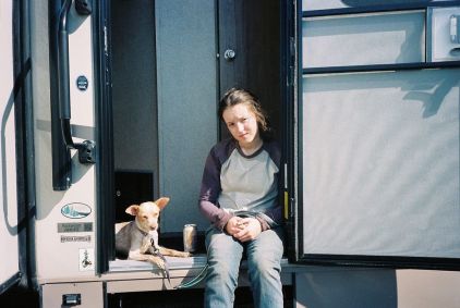 Bella Ramsey com um cachorro em trailer no set da série The Last of Us