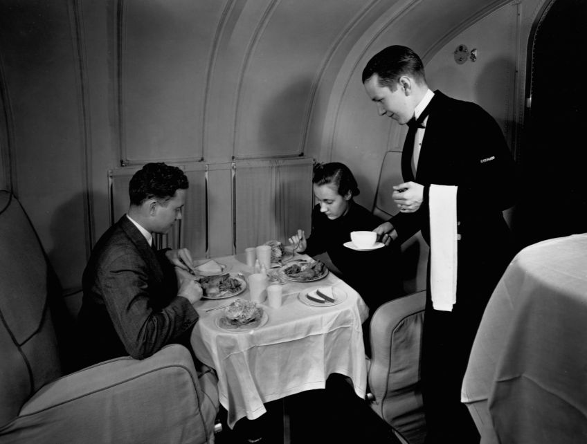 Dois passageiros jantam enquanto viajam no Pan American Martin Clipper, voando a 130 pés / Library of Congress/Corbis/VCG via Getty Images