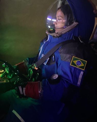 No International Institute for Astronautical Sciences, a jovem está sendo preparada para as experiências fora da órbita terrestre. Dentre os treinamentos, está o uso do traje espacial completo, que possui diversas camadas, é pesado e limita os movimentos corporais./ Reprodução