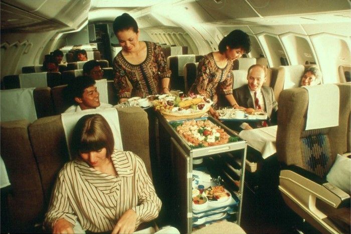 Funcionárias da Singapure Airlines servem passageiros da Business Class na década de 80 / Singapore Airlines/Arquivo