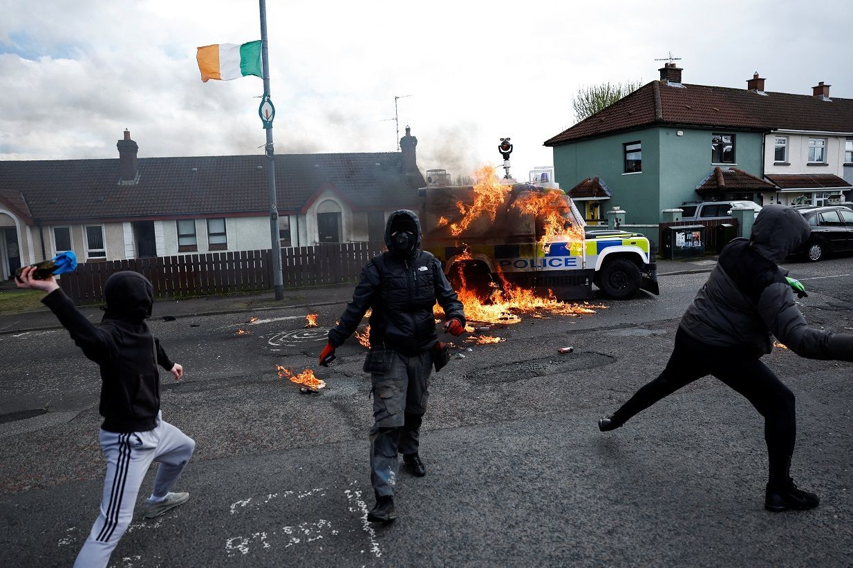 Membros do grupo nacionalista 'Republicanos dissidentes' atiram coquetéis molotov contra carro da polícia enquanto nacionalistas realizam manifestação contra acordo de paz em seu 25º aniversário, em Londonderry, Irlanda do Norte