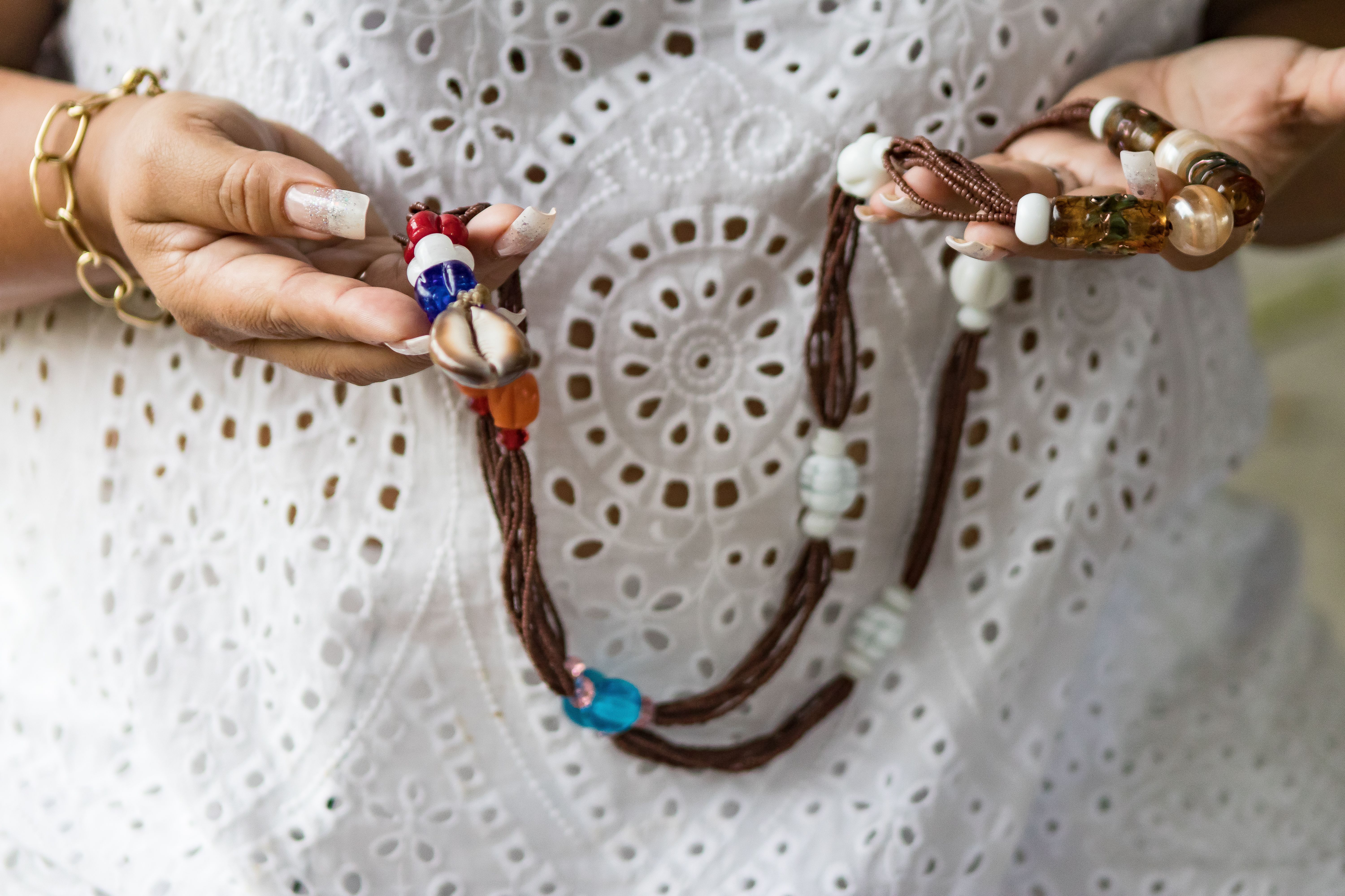 imagem de uma mulher segurando guias tradicionais de religiões de matriz africana