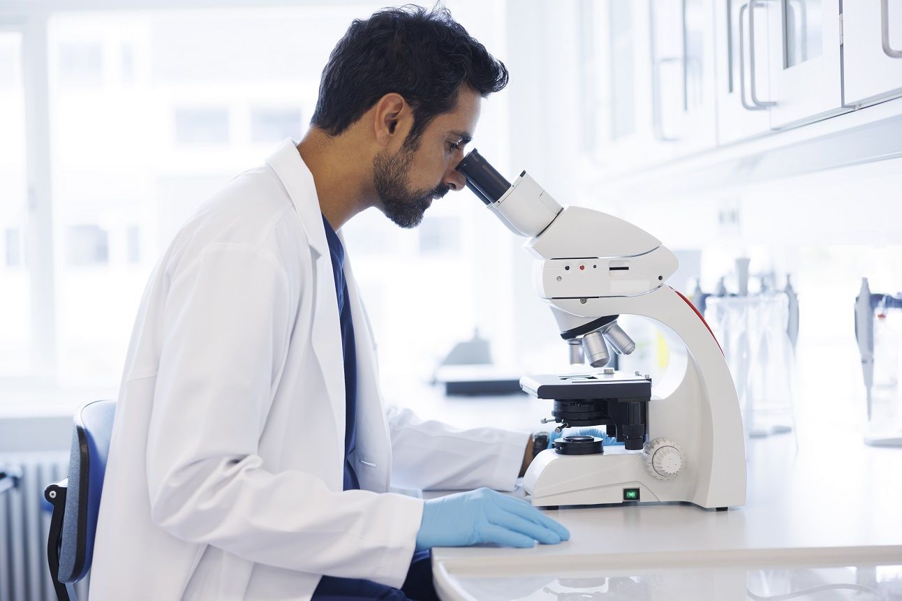 Scientist in laboratory looking into microscope