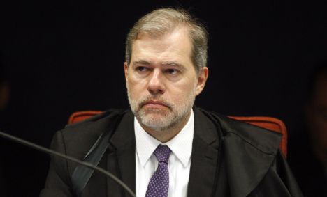 Dias Toffoli sentado, de terno, olha para a direita com expressão neutra