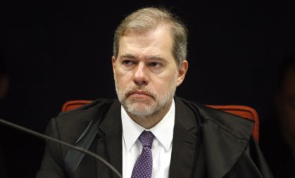 Dias Toffoli sentado, de terno, olha para a direita com expressão neutra