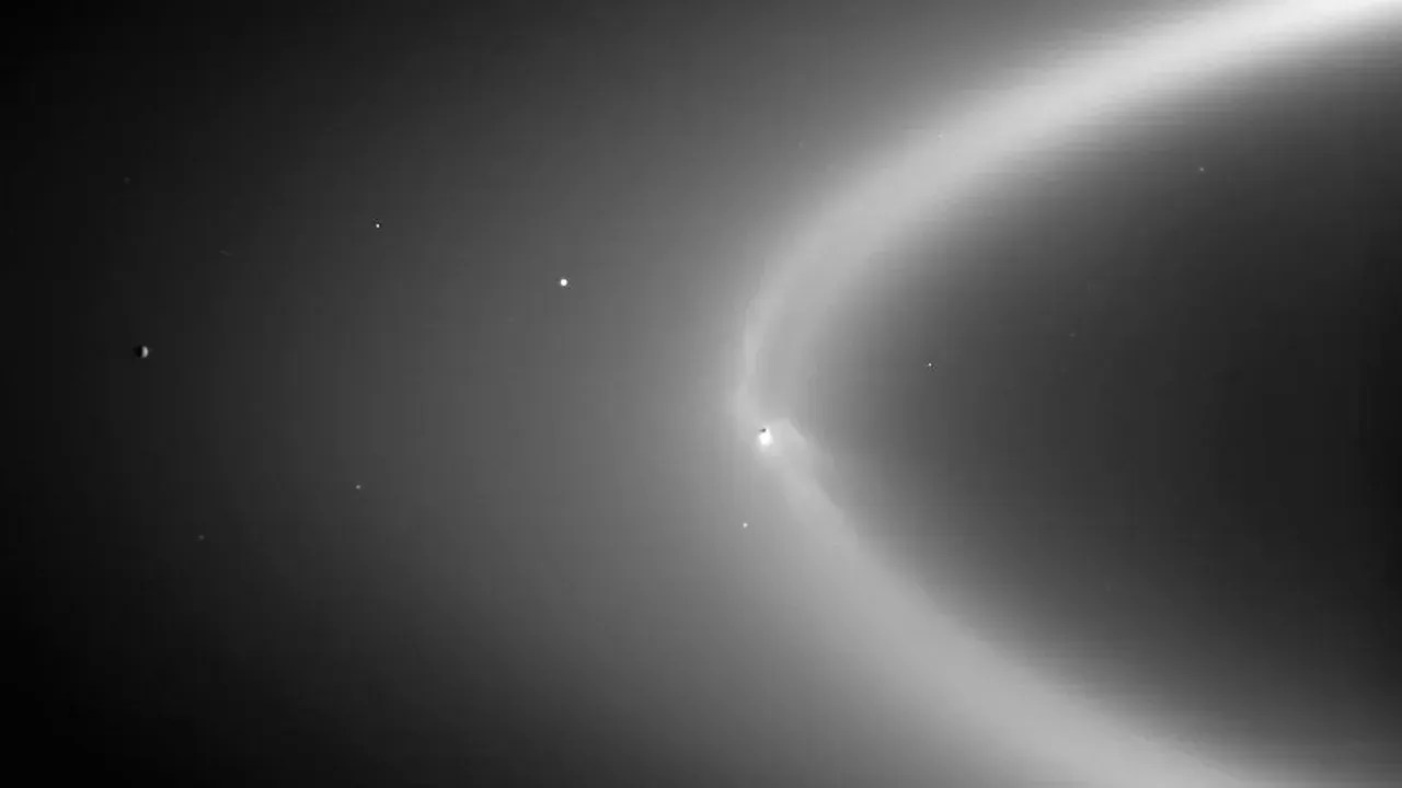 Arcos finos de material gelado se expandem de Encélado (ponto branco mais brilhante acima) para o anel E de Saturno / NASA/JPL/Space Science Institute