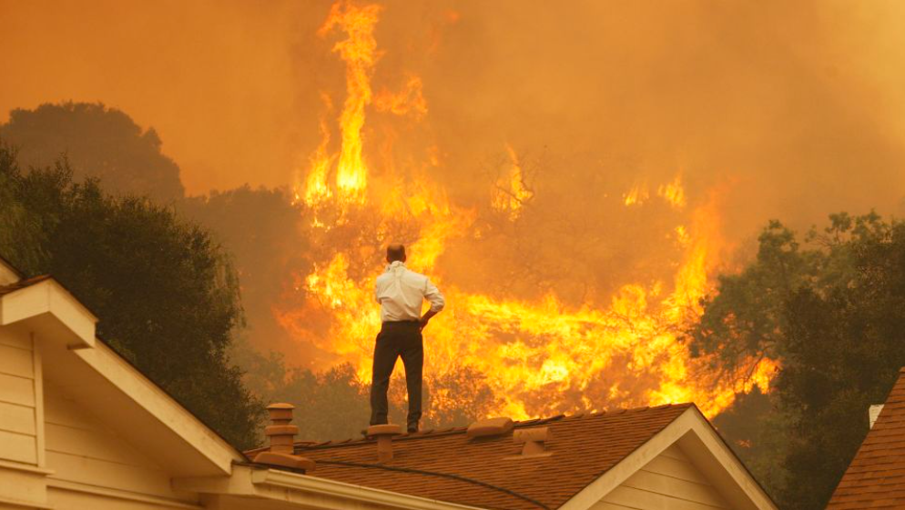 homem no telhado observando incendio florestal