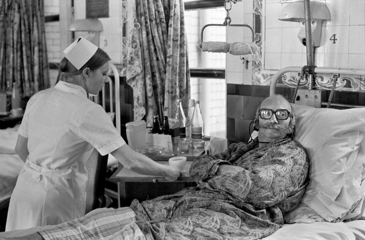 Um paciente do Hospital Charing Cross, em Londres, assiste TV com fones de ouvido em 1972
