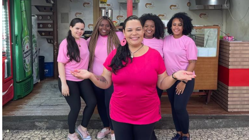 Drica, empreendedora responsável pelo acarajé rosa, com suas funcionárias, à frente de uma das suas lojas / Divulgação