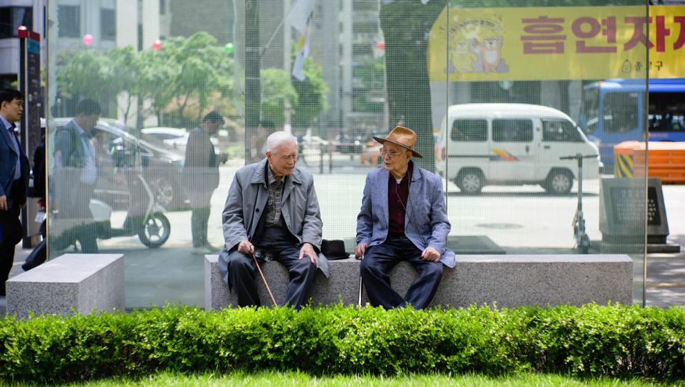 Dois idosos conversam em um banco em Seul, Coreia do Sul