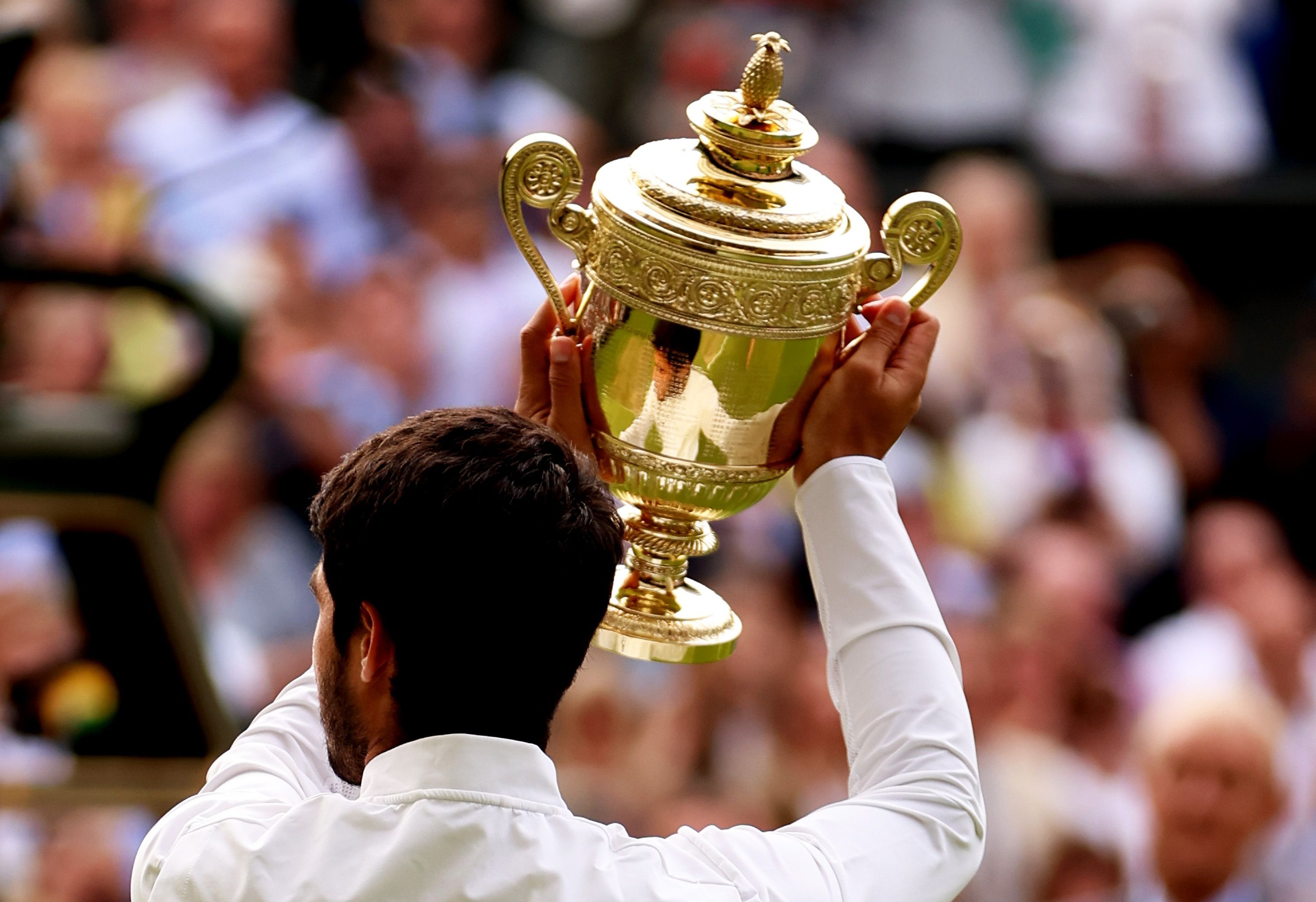 O tenista espanhol Carlos Alcaraz segura o troféu de Wimbledon, com seu distinto abacaxi, após vencer a grande final masculina em 16 de julho de 2023. / Clive Brunskill/Getty Images