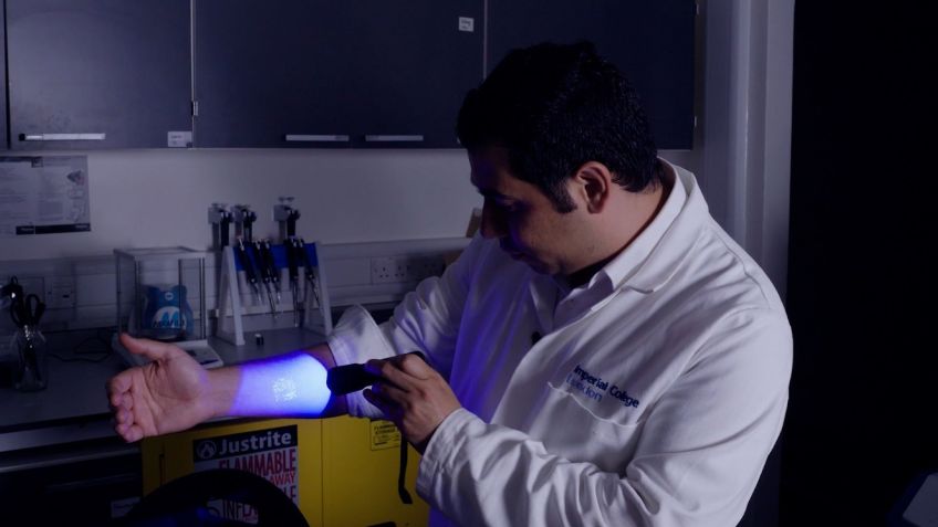 Em seu laboratório no Imperial College de Londres, Ali Yetisen demonstra um carimbo em seu braço criado com tinta de tatuagem que brilha sob certa luz. / CNN