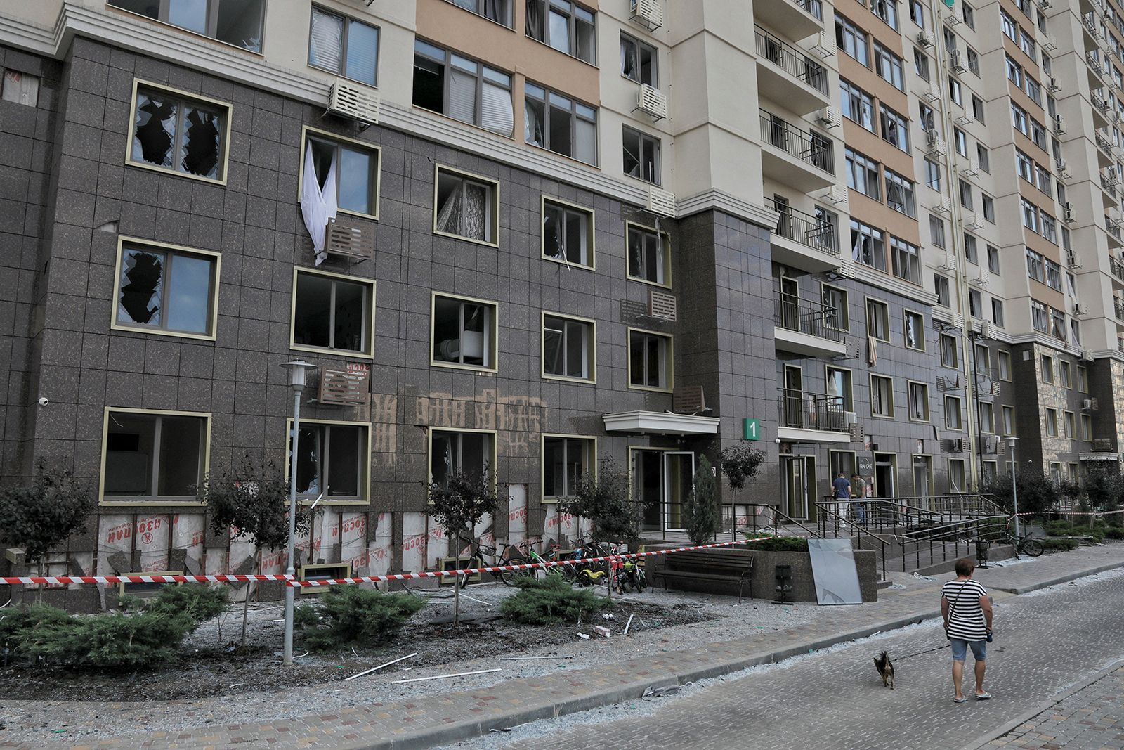 Um morador caminha com um cachorro ao lado de um prédio danificado durante ataques russos perto de Odessa, na Ucrânia, em 19 de julho. / Reuters