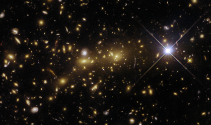 Hubble captura imagem de "lente gravitacional" que amplia objetos distantes em aglomerado de galáxias