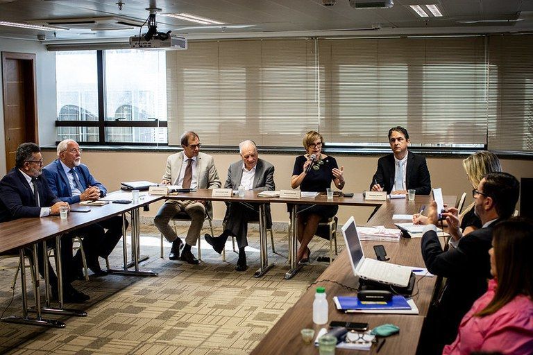 Pessoas se reúnem ao redor de mesa e debatem novo teto para MEIs em reunião do MDIC com o Comitê Técnico MEI, do Fórum Permanente das Microempresas e Empresas de Pequeno Porte (FPMPE)