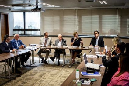Pessoas se reúnem ao redor de mesa e debatem novo teto para MEIs em reunião do MDIC com o Comitê Técnico MEI, do Fórum Permanente das Microempresas e Empresas de Pequeno Porte (FPMPE)