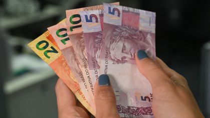 Mãos femininas manipulando dinheiro.