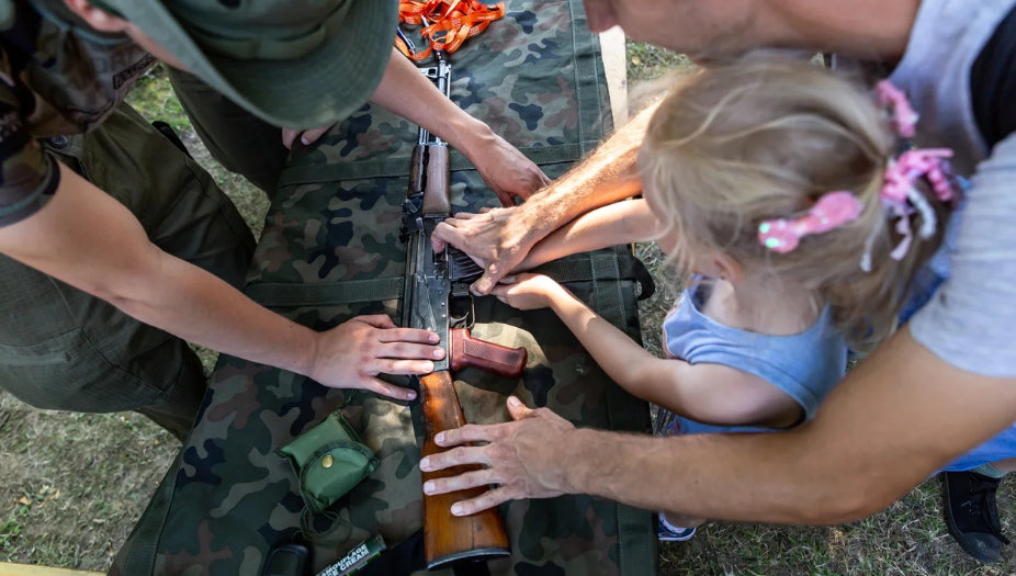 Um militar polonês mostra uma arma para crianças durante um festival militar, parte das comemorações do Dia do Exército Polonês em Polanka Wielka no domingo / Dominika Zarzycka/NurPhoto/Getty Images