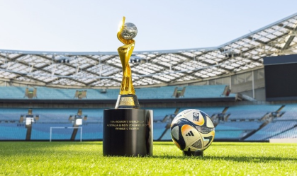 Em um estádio, é possível ver a taça da Copa ao lado da bola da final
